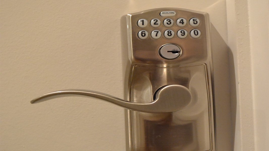 A satin-finished electronic door lock with white buttons and black numbers