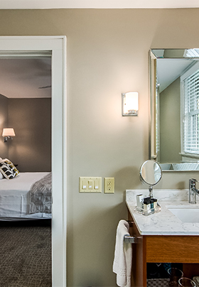 Interior view from the en suite bathroom of Room Four into the bedroom showing crisp, white linens