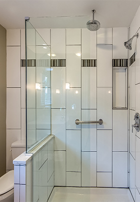 Looking into the glass walled shower, with rainfall showerhead and grab bar