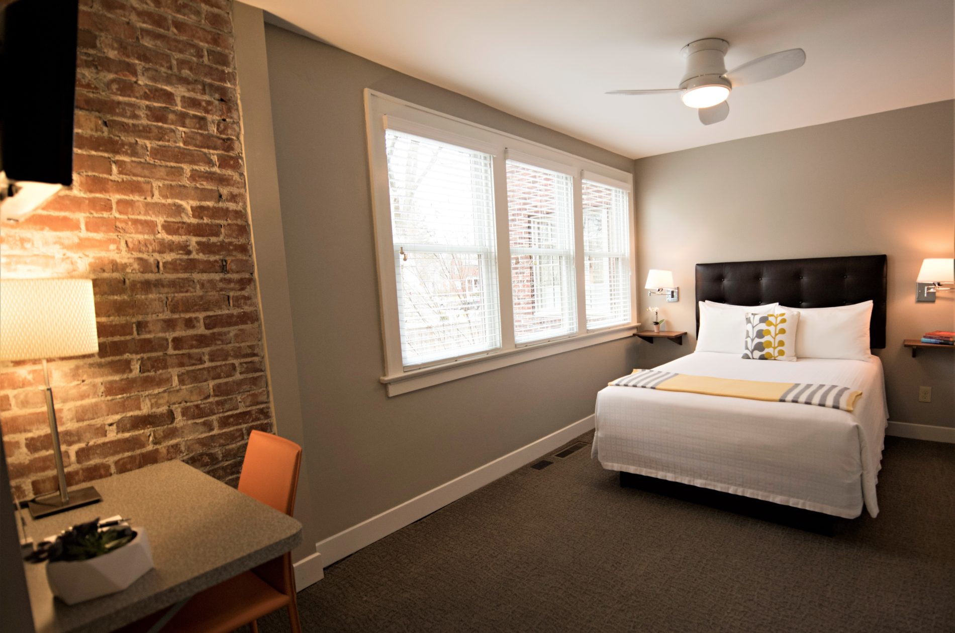 Looking into Room Three with view of red interior brick, bed and sunlit windows