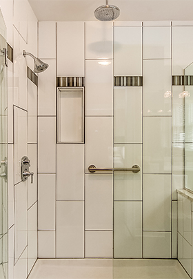 Walk-in shower in Room Three showing glass walls and white subway tiles with gray accent tiles