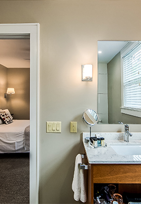 Interior view from the en suite bathroom of Room One into the bedroom showing crisp, white linens