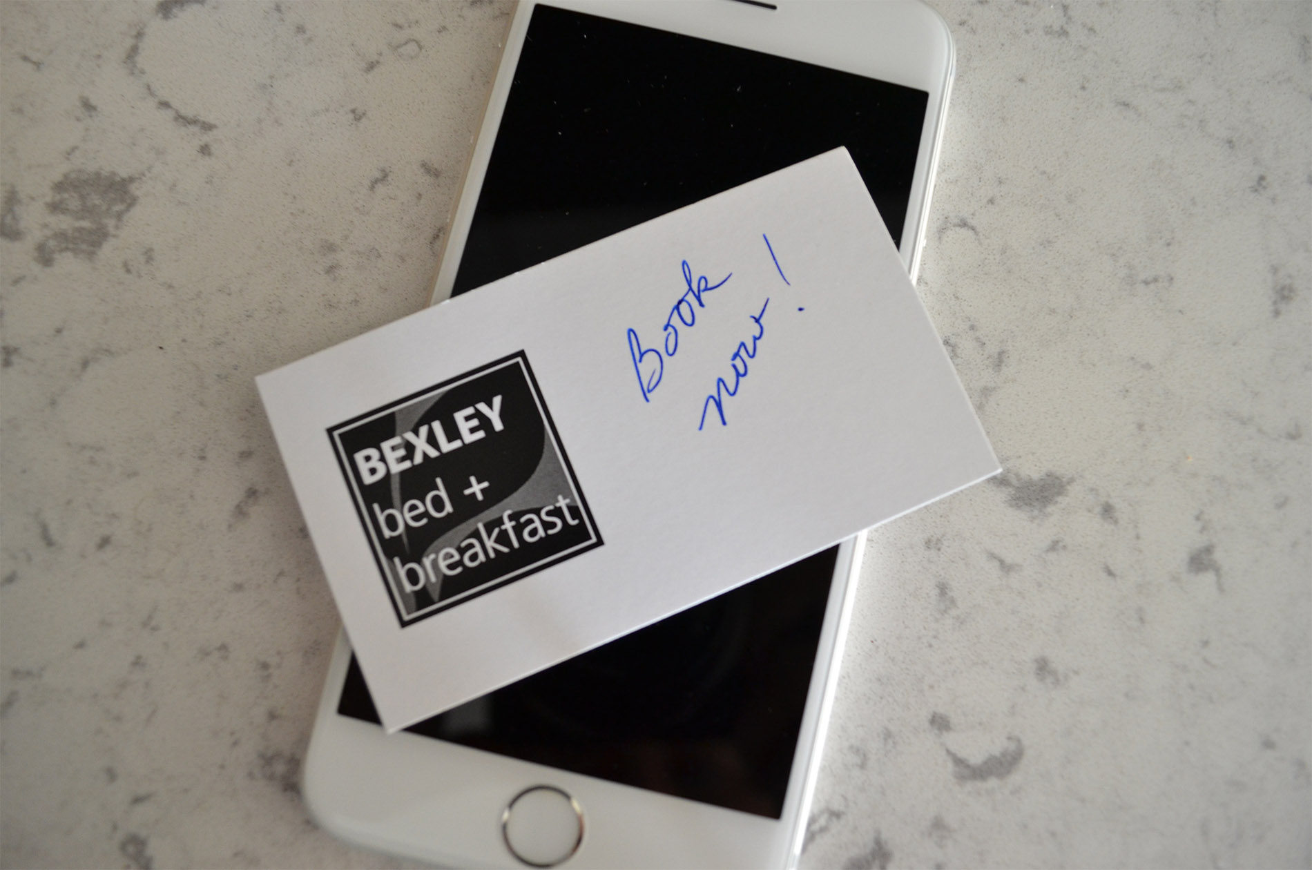 A white iPhone on a counter with a business card from the inn on top of it